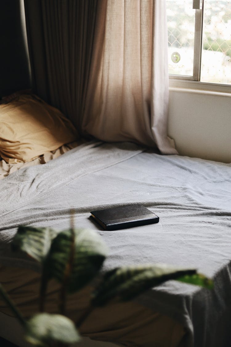 Book With A Black Leather Cover On A Bed