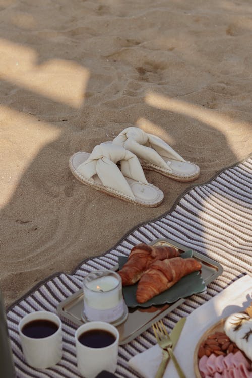 Free Sandals, Croissants and Coffee on a Towel on a Beach Stock Photo