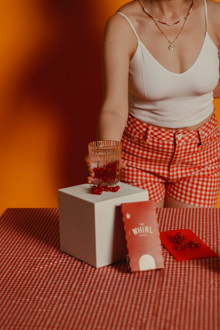 Woman Putting A Glass Of Juice On A White Box 