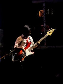 A musician playing bass guitar on stage during a live concert, creating an engaging atmosphere.