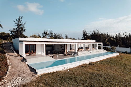 White Concrete House Near Green Trees Under Blue Sky