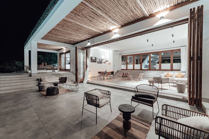 The open living room lit at night, seen from the terrace
