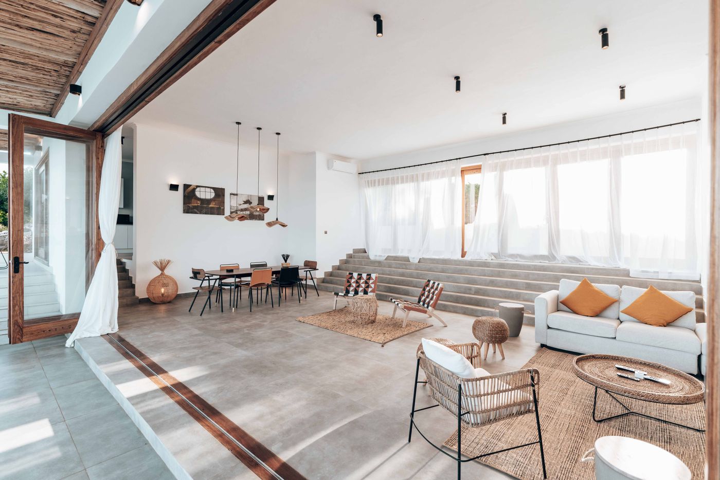 Living and dining room with wide concrete steps used as seating and sheer curtains