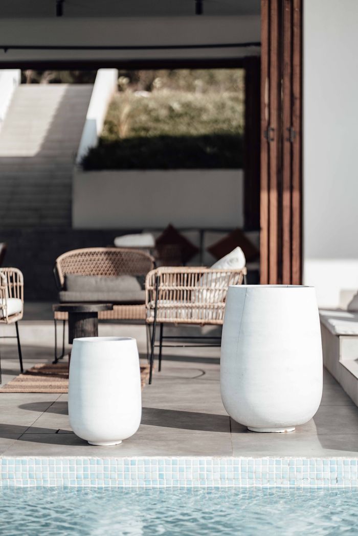 Two white ceramic planters at the edge of the pool