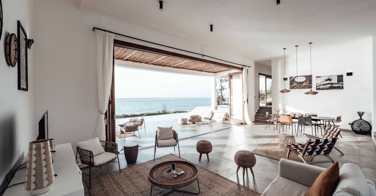 A spacious, minimalistic living room with a stunning ocean view, showcasing modern interior design.
