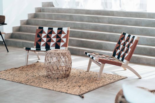 Stylish indoor scene featuring modern chairs and a woven basket table on a textured rug.