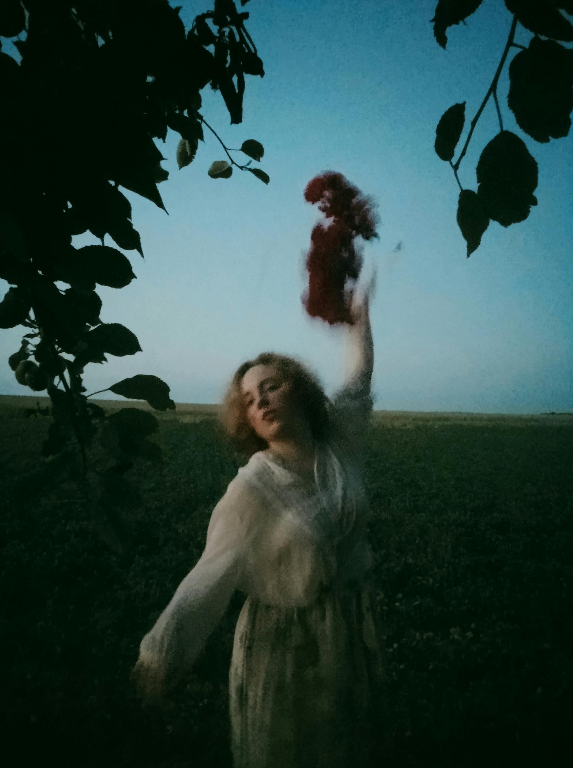Blurred motion portrait of a woman in a rustic countryside setting, conveying freedom and art.