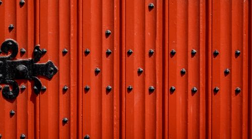 Free Close-up of a textured red iron door adorned with black knobs and intricate patterns. Stock Photo