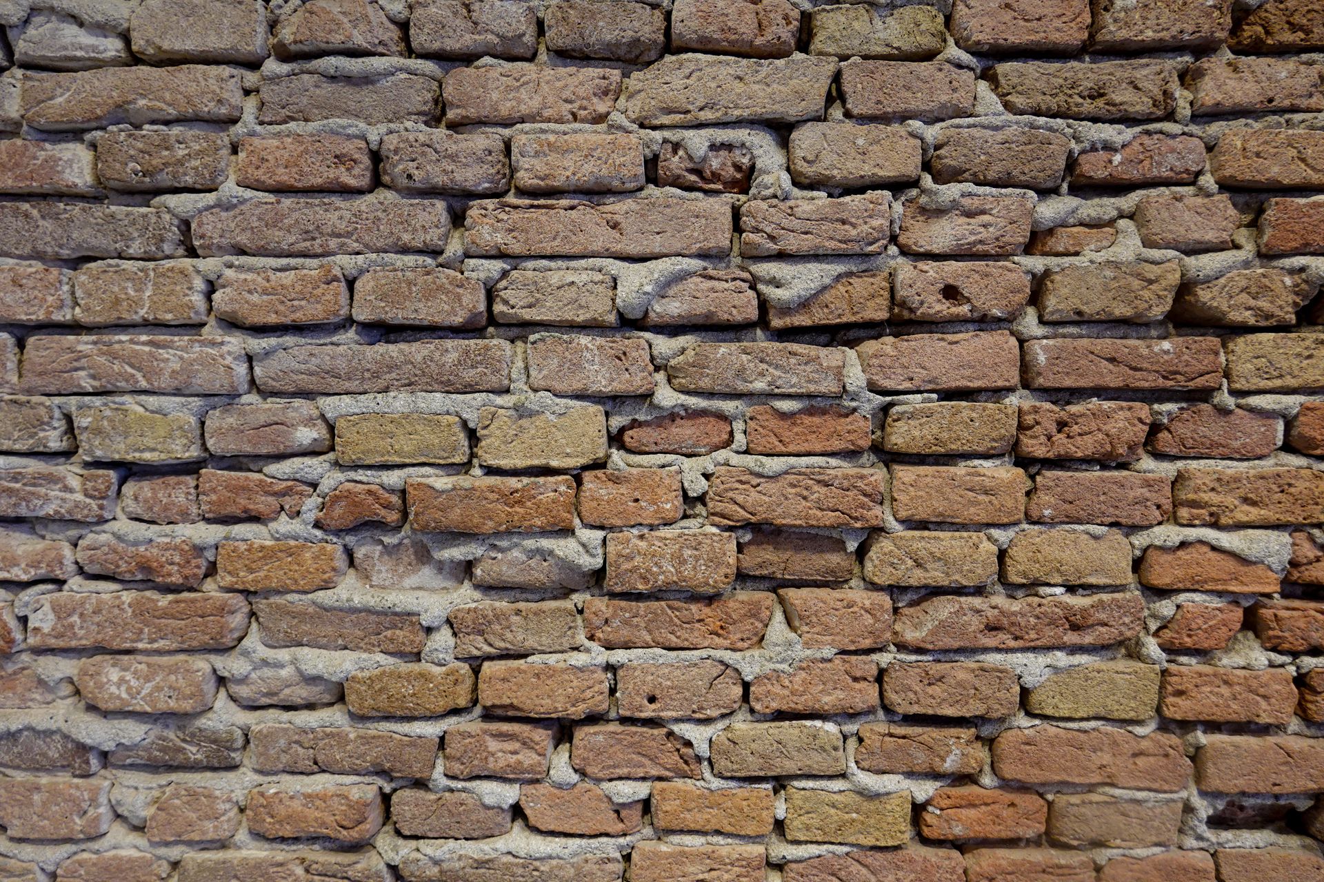 Close-up of a red brick wall with rough texture and visible mortar seams.