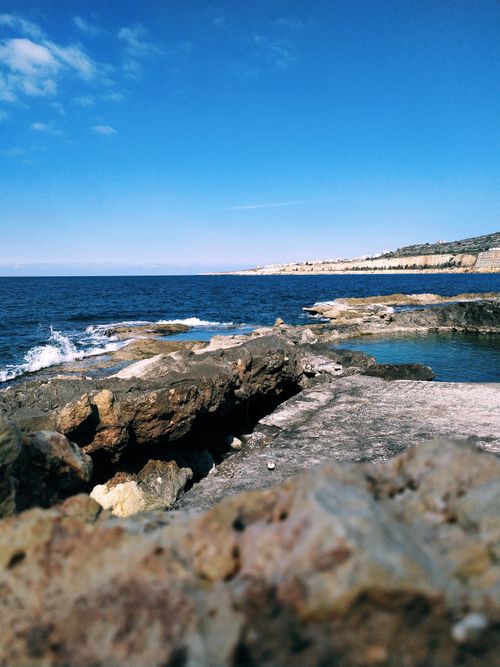 Free Explore breathtaking rock formations along a stunning ocean coastline under a vibrant blue sky. Stock Photo