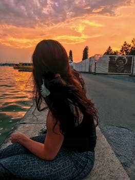 楚格湖畔，一位长发女子坐着，欣赏着充满活力的日落天空