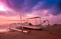 日出时分，传统的船在宁静的海滩上休息，天空色彩充满活力