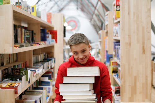Smiling Boy Holding Pile of Books