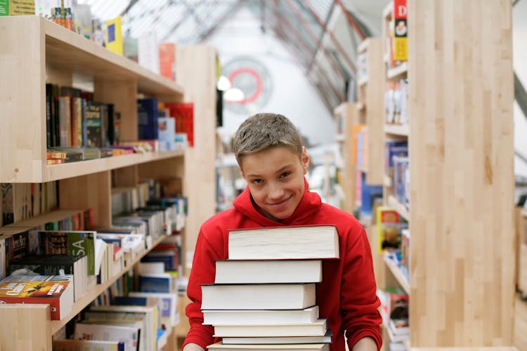 Smiling Boy Holding Pile Of Books