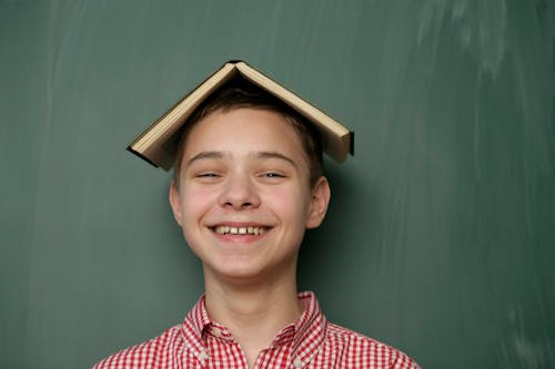 Smiling Boy Posing With Book on His Head