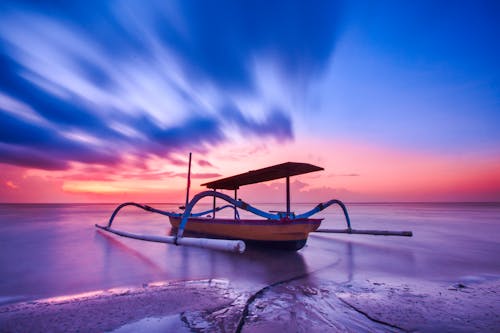 Perahu Kayu Coklat Biru Dan Putih Saat Matahari Terbenam Oranye