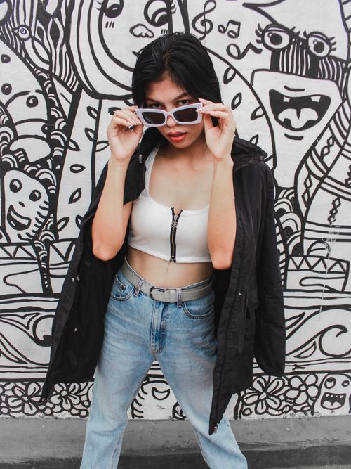 Free Fashion-forward Asian woman posing against vibrant street art in Davao, Philippines. Stock Photo