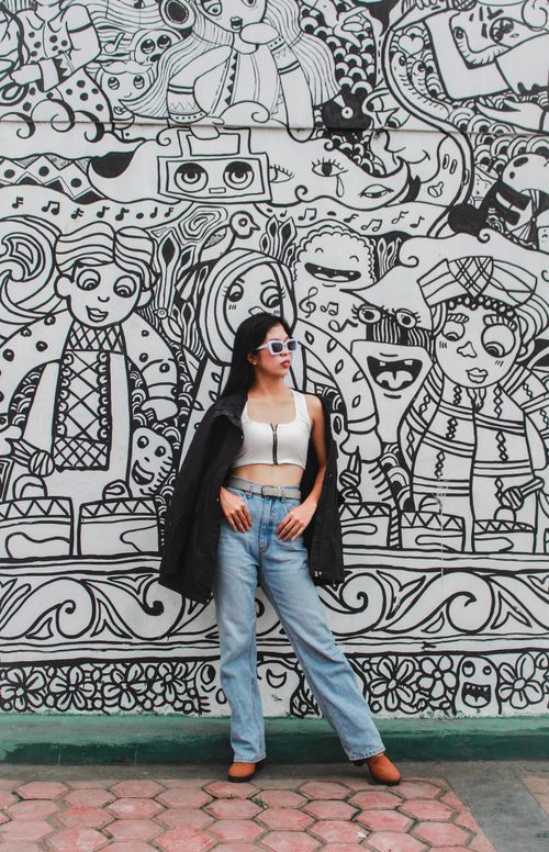 Free Stylish woman posing in front of an intricate black and white mural, blending fashion and art. Stock Photo