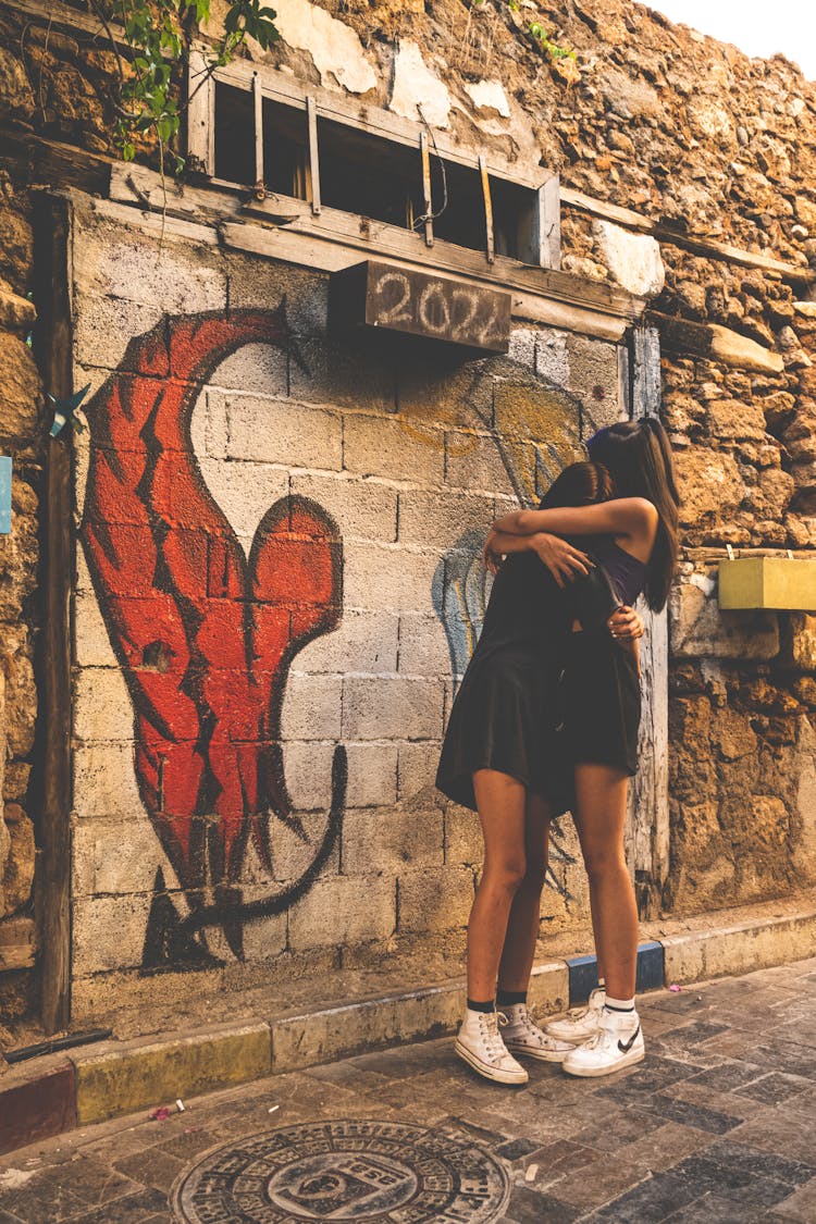 Girls Embracing Against Mural