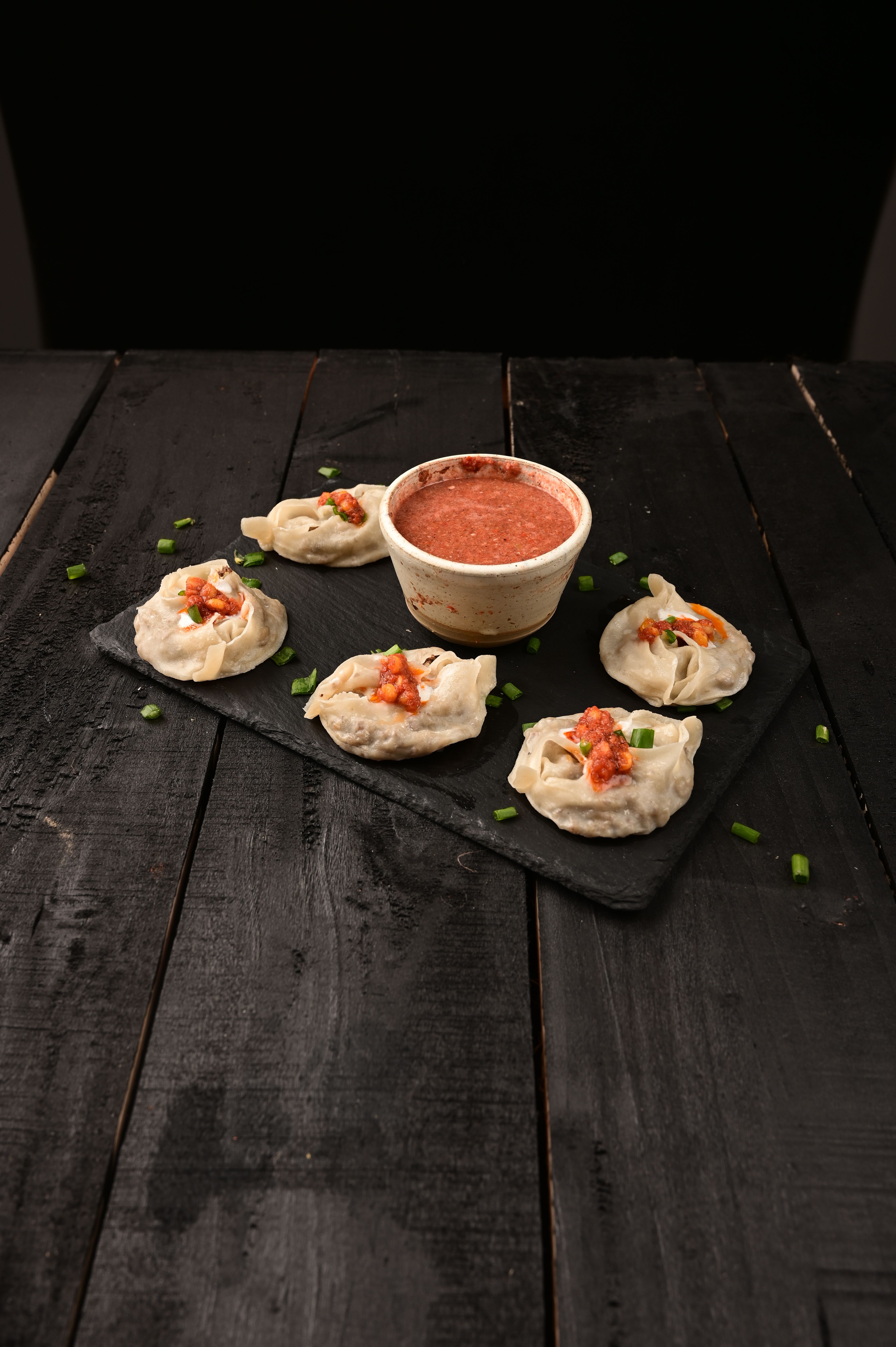 Savor the taste of Afghan mantu dumplings served with a spicy tomato sauce on a rustic surface.