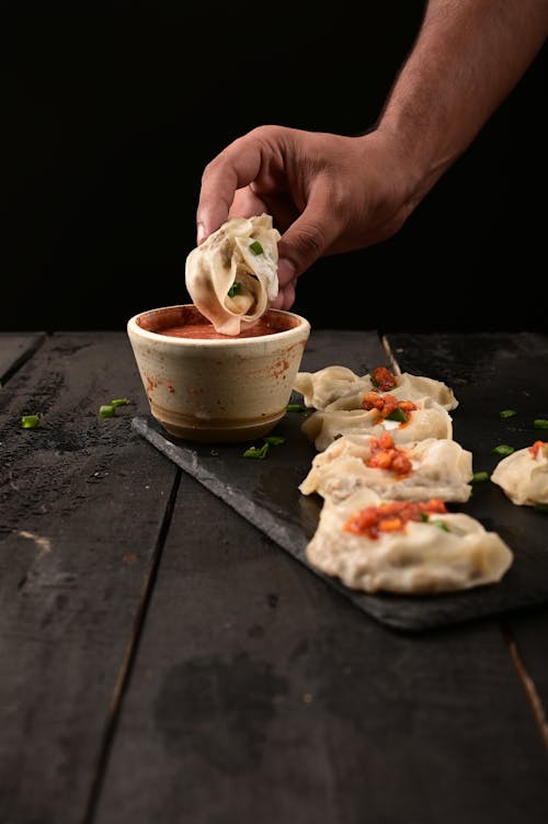 Food in Man Hand over Bowl with Sauce