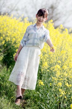 阳光下，年轻女孩快乐地在充满活力的黄色花田里摆姿势