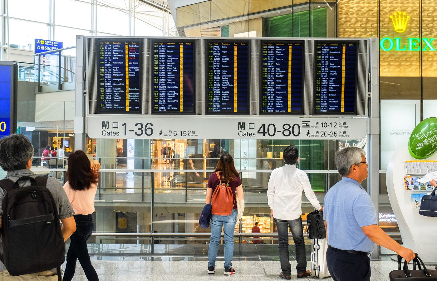 Passengers checking the departure board at Hong Kong International Airport terminal.