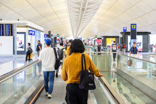 Passengers walking through a modern airport terminal in Hong Kong, capturing the essence of travel.