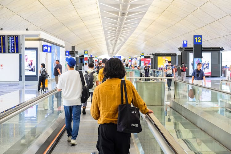 View Of A Busy Airport Building With People Walking Around With Luggage 