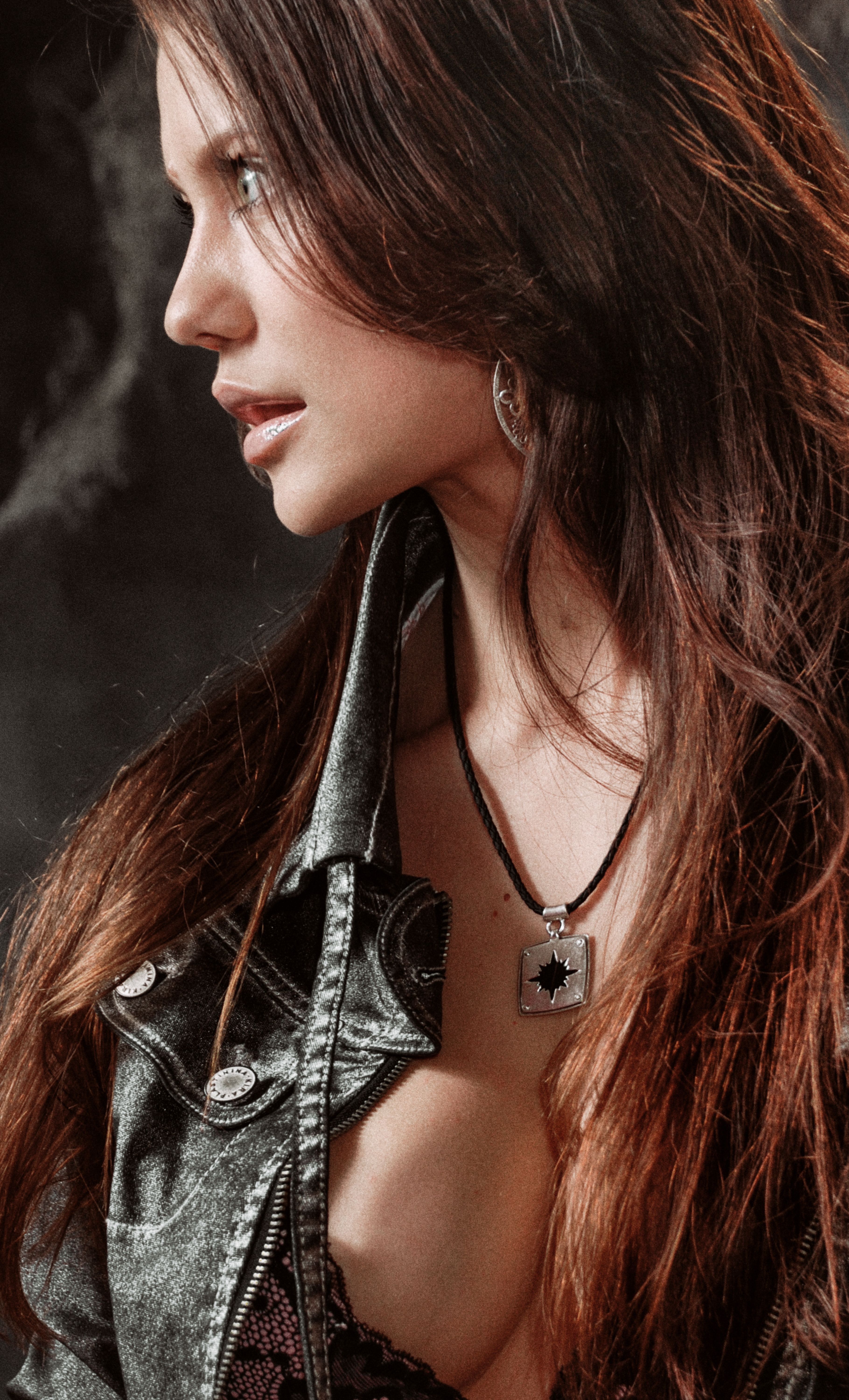Side profile portrait of a stylish woman wearing a denim jacket and necklace, showcasing modern fashion.