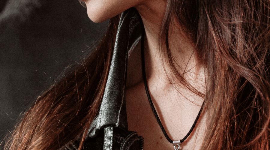 Femme en veste noire portant un collier fin et des boucles d'oreilles discrètes pour une tenue de travail élégante