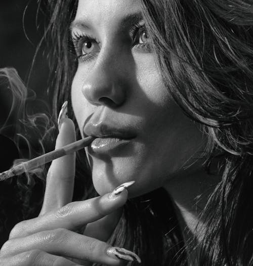 Grayscale Photo of a Beautiful Woman Smoking Cigarette