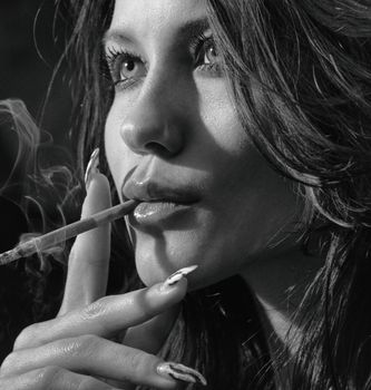 Close-up black and white portrait of a woman smoking, conveying moody elegance.