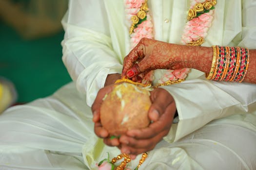Close-up of a couple performing a traditional Indian wedding ritual with henna-adorned hands and jewelry.