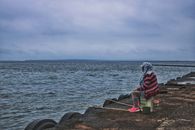 A lone fisherman sits by the ocean, enjoying a serene day of fishing. Perfect for tranquil lifestyle scenes.