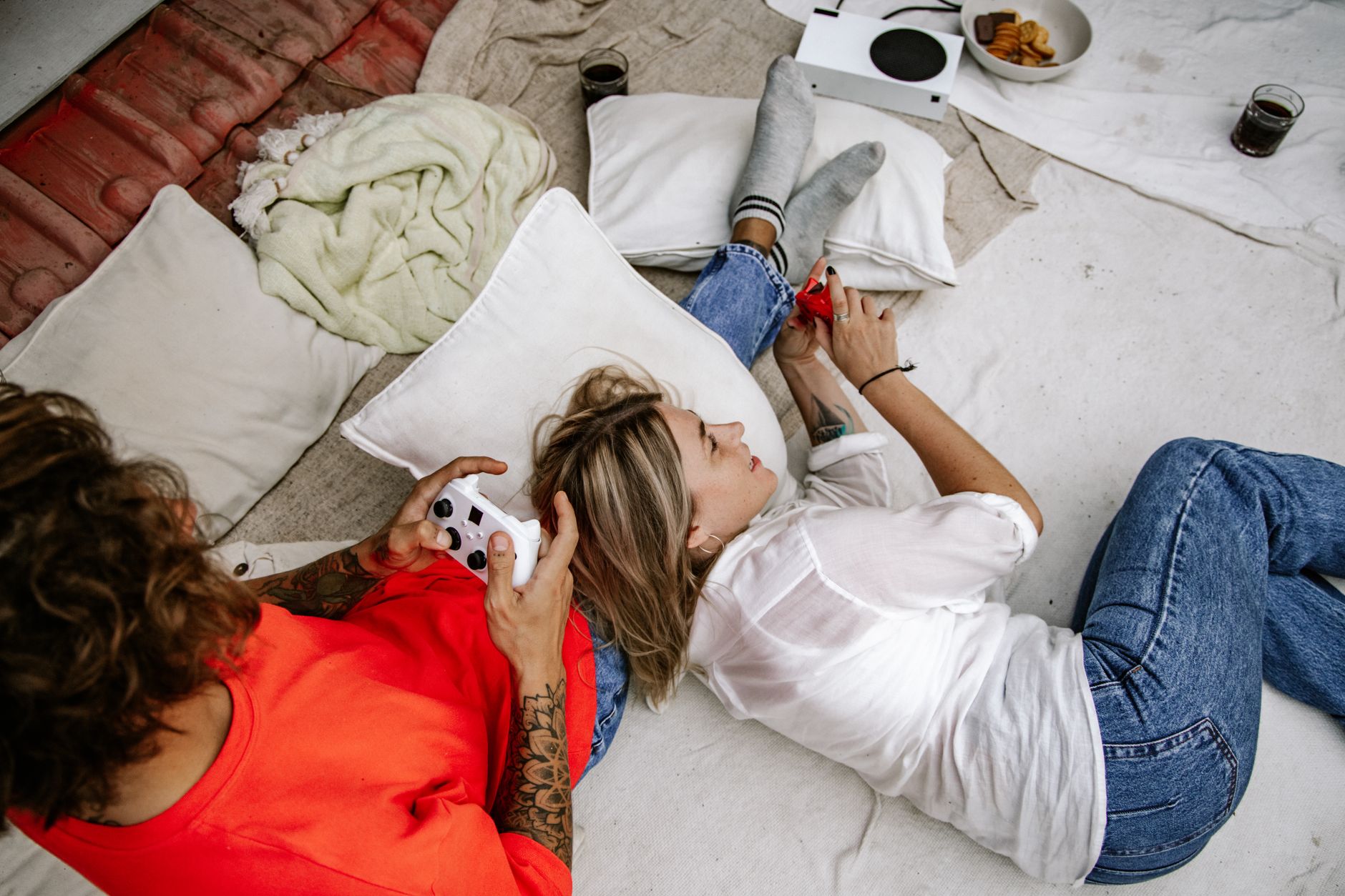 Two friends enjoying a relaxed gaming session indoors, playing on a console.
