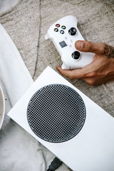 Close-up photo of a hand holding a white game controller with a console in view.