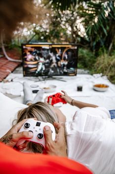 Relaxed couple playing video games outdoors, creating a cozy gaming experience.