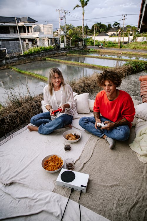Women Sitting Outdoors on a Blanket and Eating Snacks 