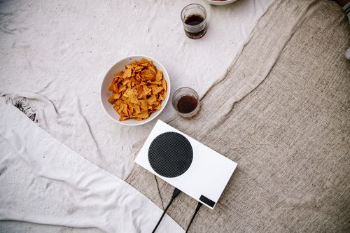 Free A cozy setup with chips, drinks, and a game console on a cloth fabric background. Perfect for relaxation. Stock Photo