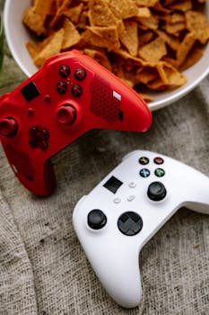 Red and white game controllers next to a bowl of chips, perfect for gamers.