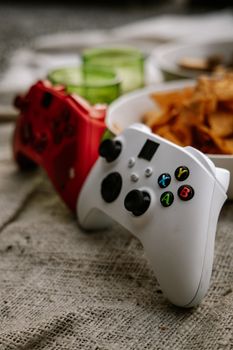 Close-up view of a white and red gaming controller with snacks in the background, perfect for gaming lifestyle themes.