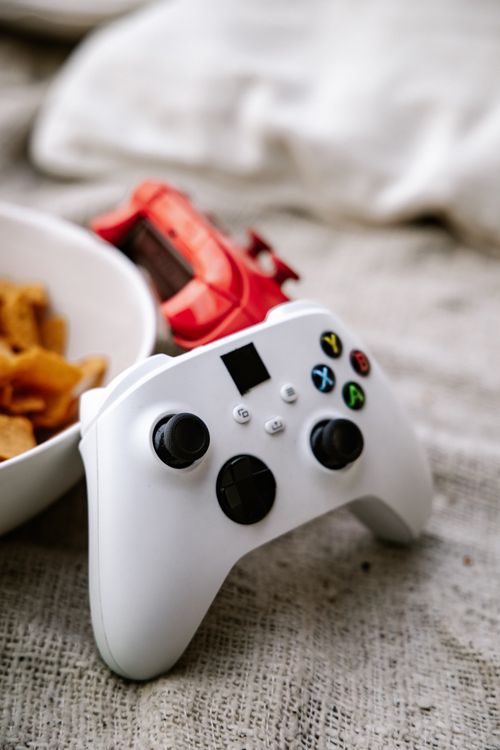 Free White and red game controllers with snacks on a textured surface. Stock Photo