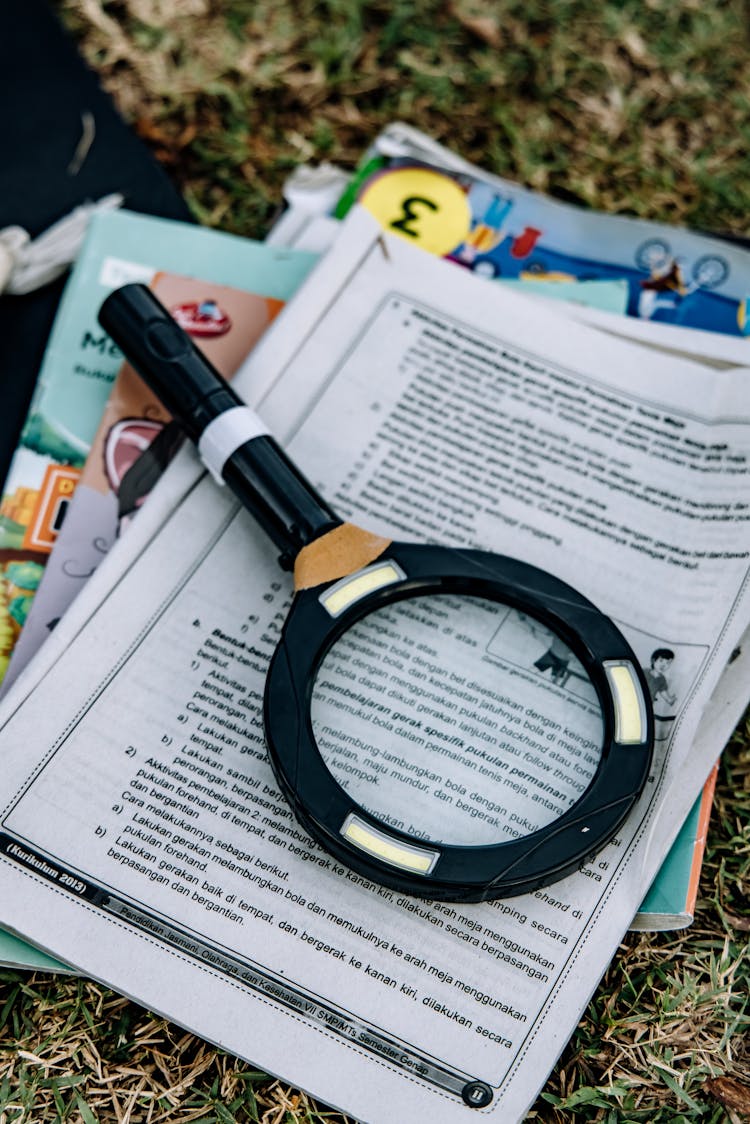 Close-Up Shot Of A Magnifying Glass On Top Of Books