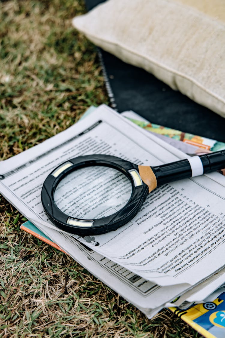 Close-Up Shot Of A Magnifying Glass On Top Of Books