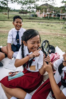 Photo by ROMAN ODINTSOV Children laughing and exploring with a magnifying glass during outdoor school activity.