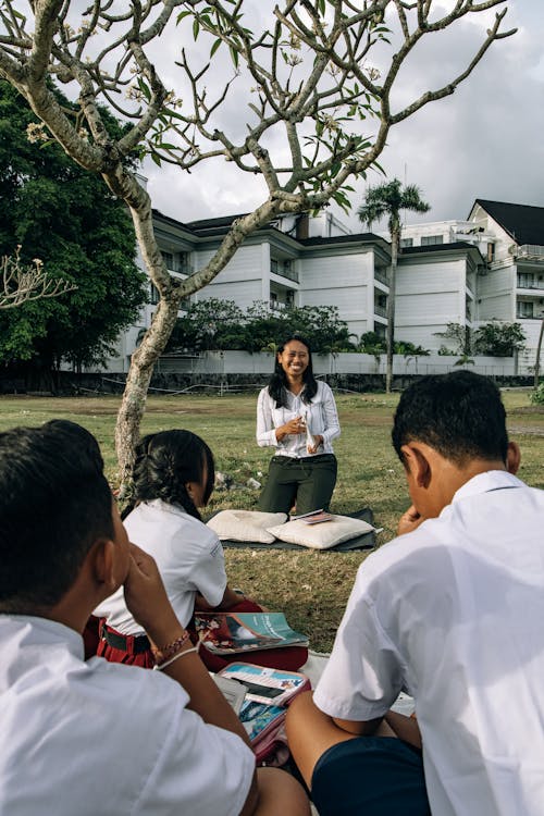 Students Sitting on a Grassy Field