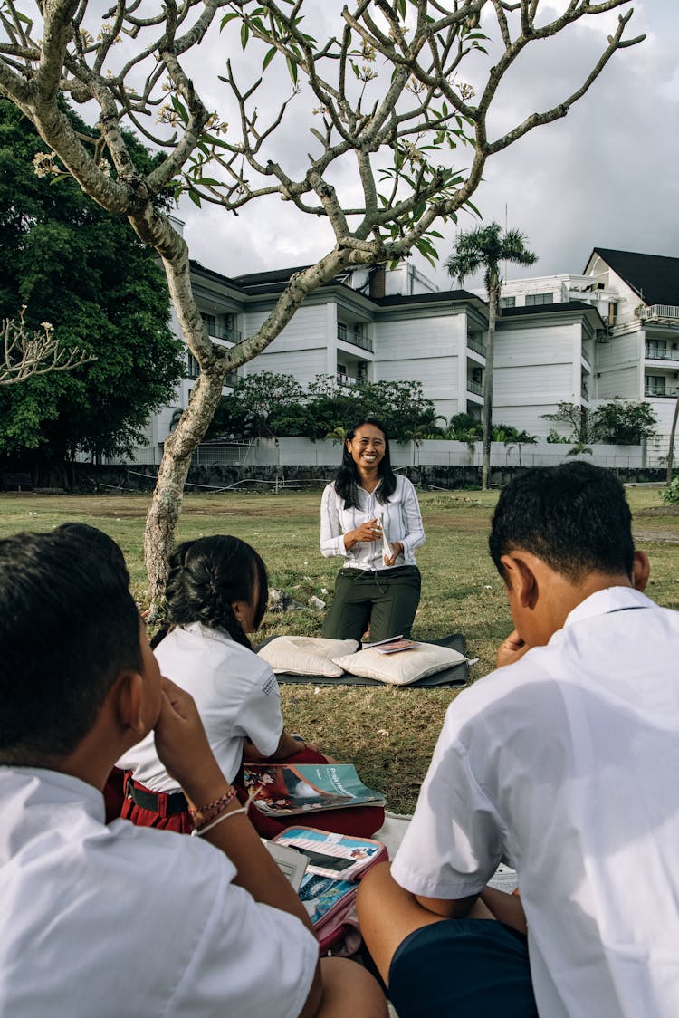 A Group Of Students Sitting On A Grassy Field