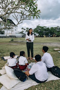 Engaging outdoor teaching session with students and teacher in a grassy field.