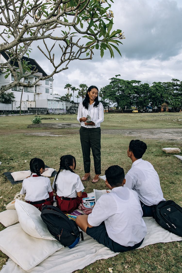 A Group Of Students Sitting On A Grassy Field